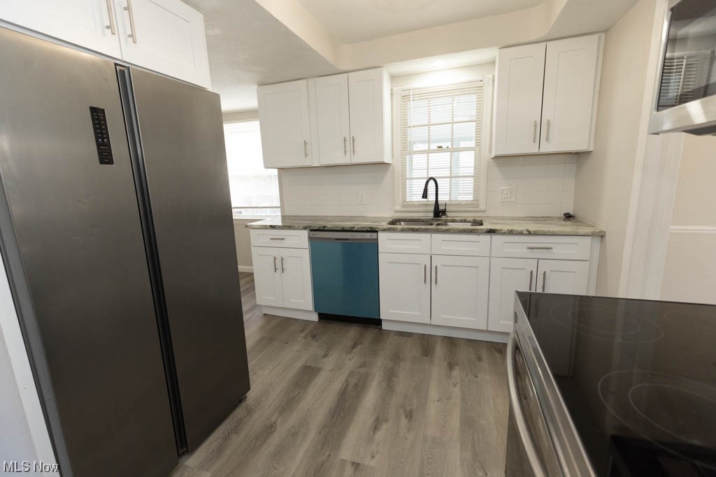3890 Wallingford Road South Euclid, OH 44121 - Photo 6 of 19 Kitchen featuring sink, light hardwood / wood-style floors, appliances with stainless steel finishes, and white cabinets