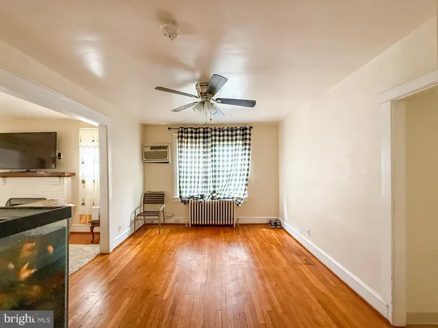 a view of empty room with wooden floor and fan