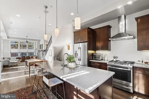 a kitchen with stainless steel appliances granite countertop a stove a refrigerator a kitchen island a table and chairs