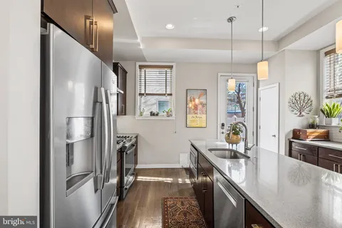 a kitchen with stainless steel appliances granite countertop a refrigerator a sink and a stove