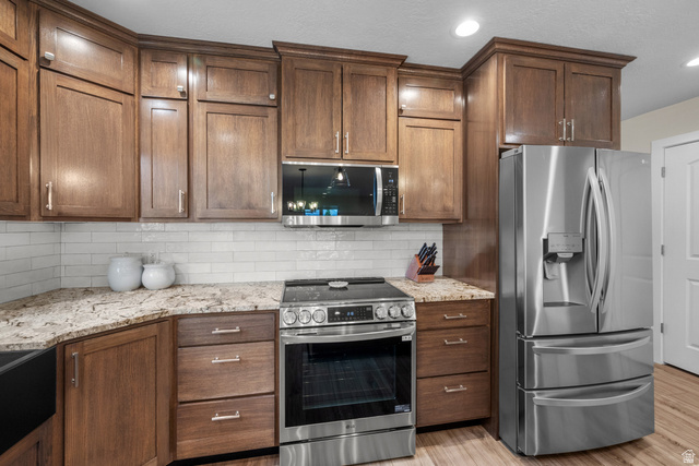 1896 West 800 North Mapleton, UT 84663 - Photo 9 of 55 Kitchen featuring stainless steel appliances, light stone countertops, tasteful backsplash, light wood finished floors, and recessed lighting