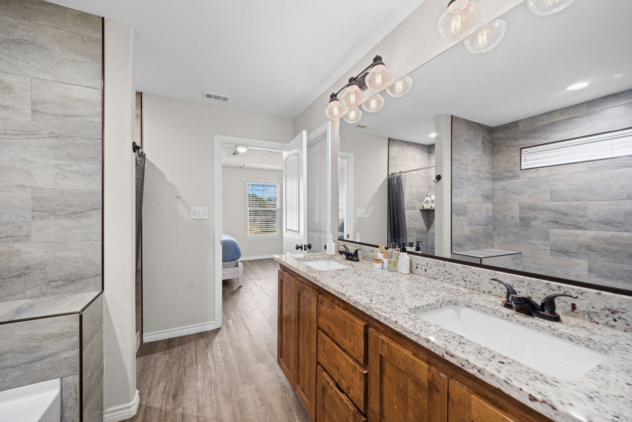 1313 Sandstone Cove Lampasas, TX 76550 - Photo 7 of 25 a bathroom with a granite countertop double vanity sink a mirror and a shower