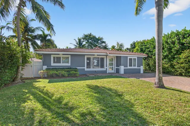 a view of a house with a yard and palm trees