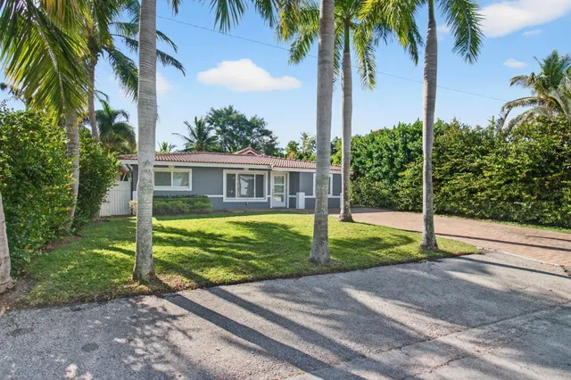 a view of a house with palm trees and a small yard