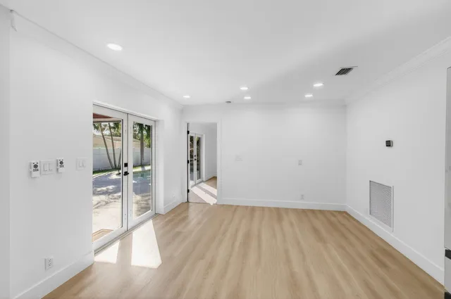 an empty room with wooden floor ceiling fan and windows