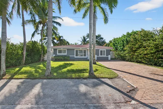 a view of a house with a yard and palm trees