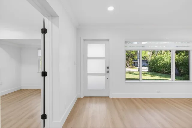 a view of an empty room with a window and wooden floor