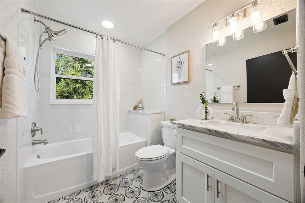 1001 Alton Avenue Orlando, FL 32804 - Photo 15 of 20 a bathroom with a granite countertop sink toilet a large mirror a shower and a bathtub