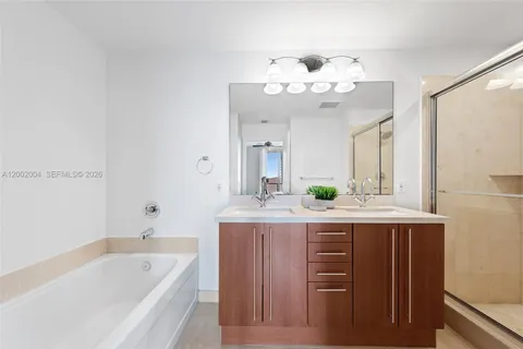 a bathroom with a granite countertop sink a large mirror and a bathtub