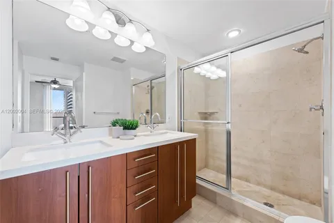 a bathroom with a double vanity sink mirror and shower