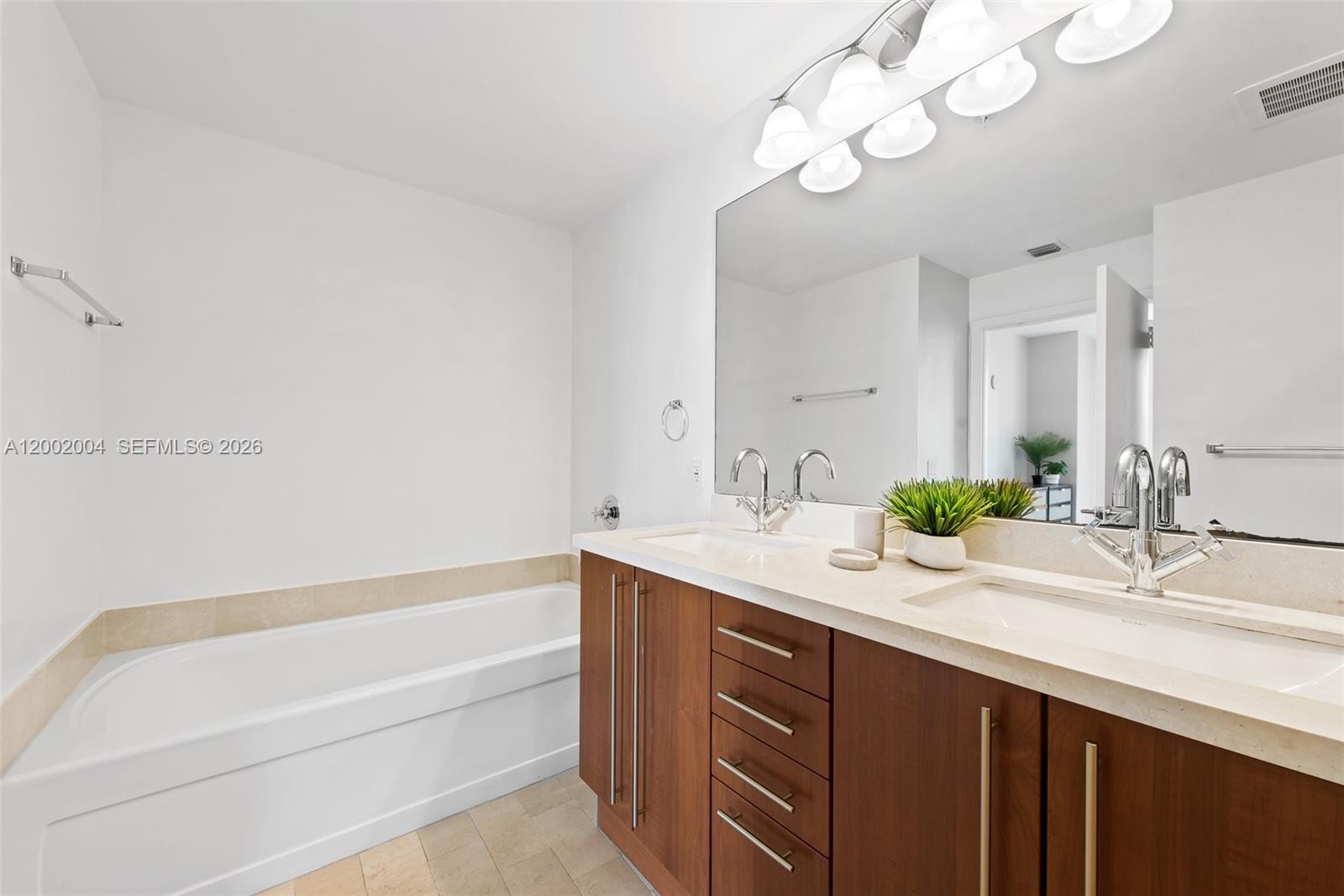 79 Southwest 12th Street, Unit 2503S Miami, FL 33130 - Photo 13 of 27 a bathroom with a granite countertop sink a large mirror and a bathtub