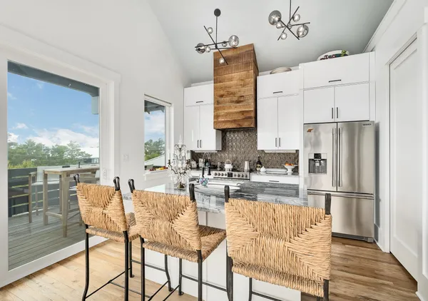 a kitchen with stainless steel appliances granite countertop a refrigerator a stove and white cabinets with wooden floors