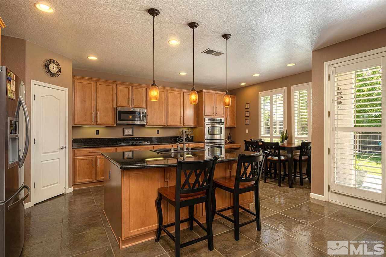 490 Oldenburg Drive Reno, NV 89521 - Photo 4 of 25 a kitchen with kitchen island granite countertop wooden cabinets and refrigerator