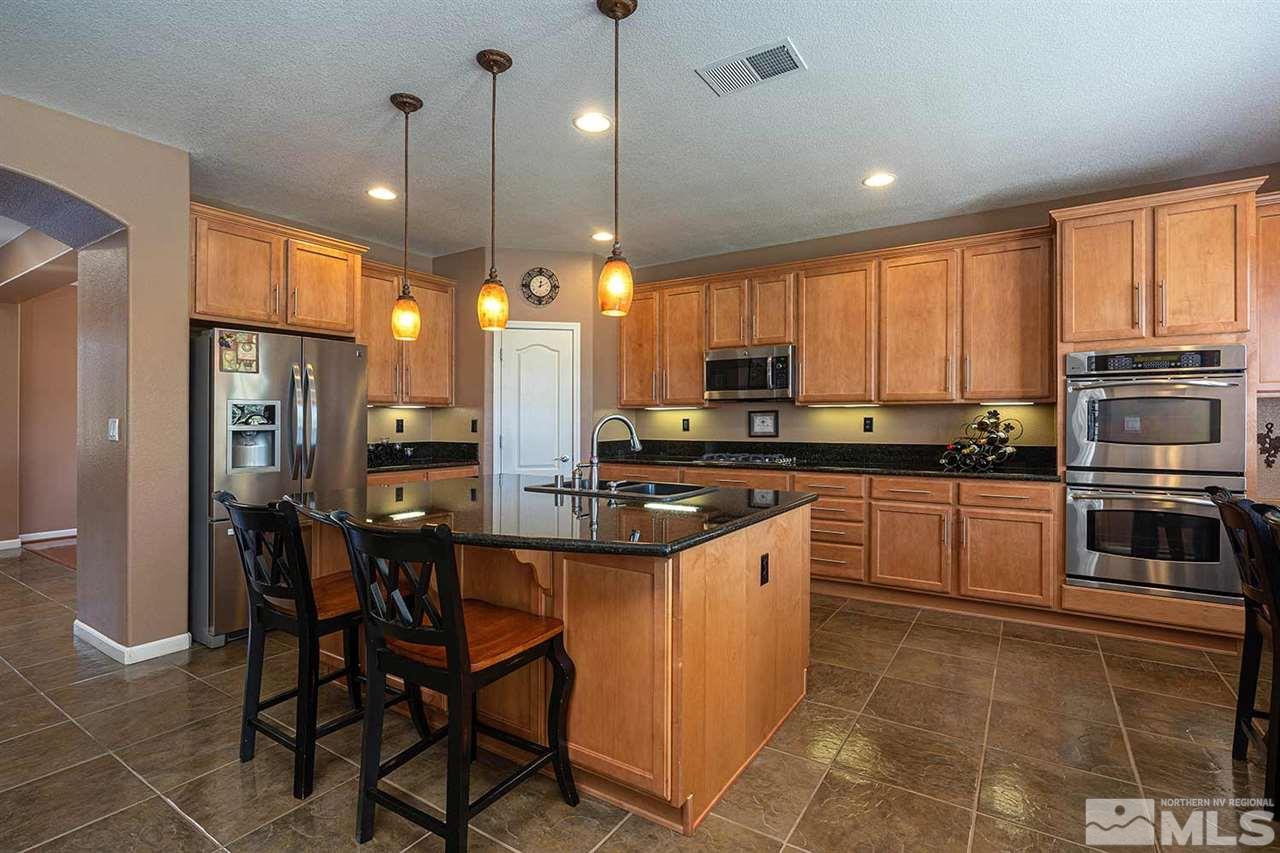 490 Oldenburg Drive Reno, NV 89521 - Photo 5 of 25 a kitchen with stainless steel appliances granite countertop a stove top oven a sink dishwasher a dining table and chairs with wooden floor