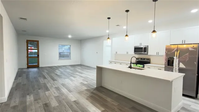 a large kitchen with kitchen island a counter space a sink a window and stainless steel appliances