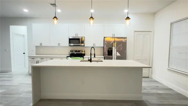 a kitchen with stainless steel appliances a sink a stove a refrigerator and cabinets