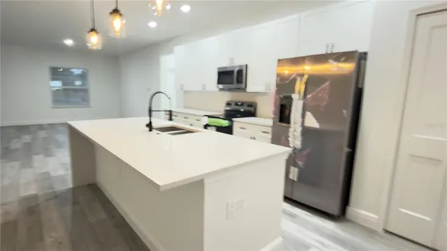 a kitchen with stainless steel appliances a white refrigerator a sink a stove and a refrigerator with wooden floor