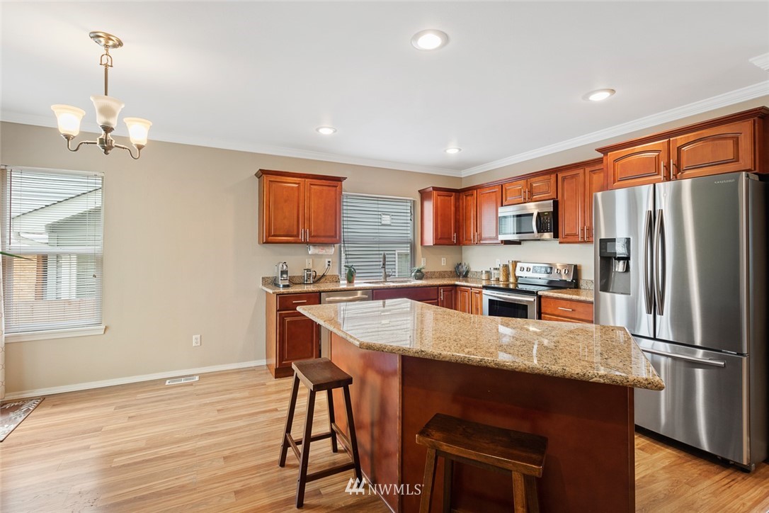 3711 Northeast 6th Street Renton, WA 98056 - Photo 8 of 20 a kitchen with granite countertop a refrigerator a stove a sink dishwasher a dining table and chairs with wooden floor