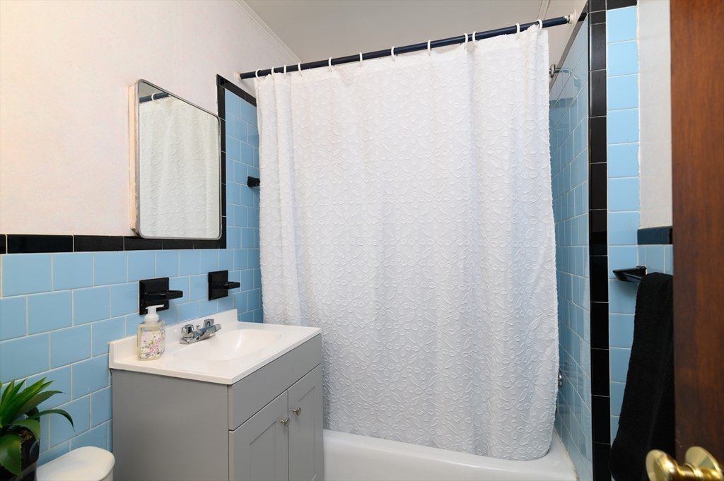 30 Puritan Road Weymouth, MA 02189 - Photo 12 of 34 a bathroom with a sink a mirror and a shower curtain