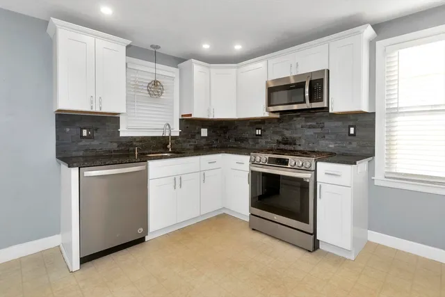 a kitchen with white cabinets stainless steel appliances and window