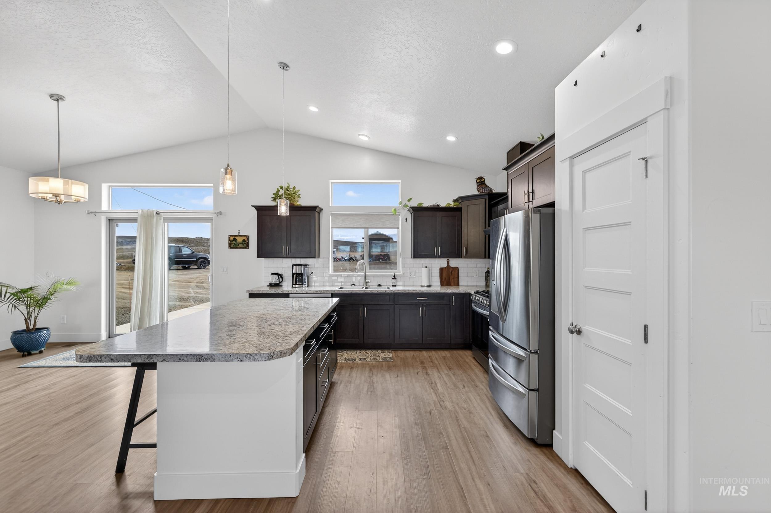1854 Jacks Road Midvale, ID 83645 - Photo 3 of 16 Kitchen with a kitchen bar, stainless steel appliances, backsplash, decorative light fixtures, and light wood-style floors