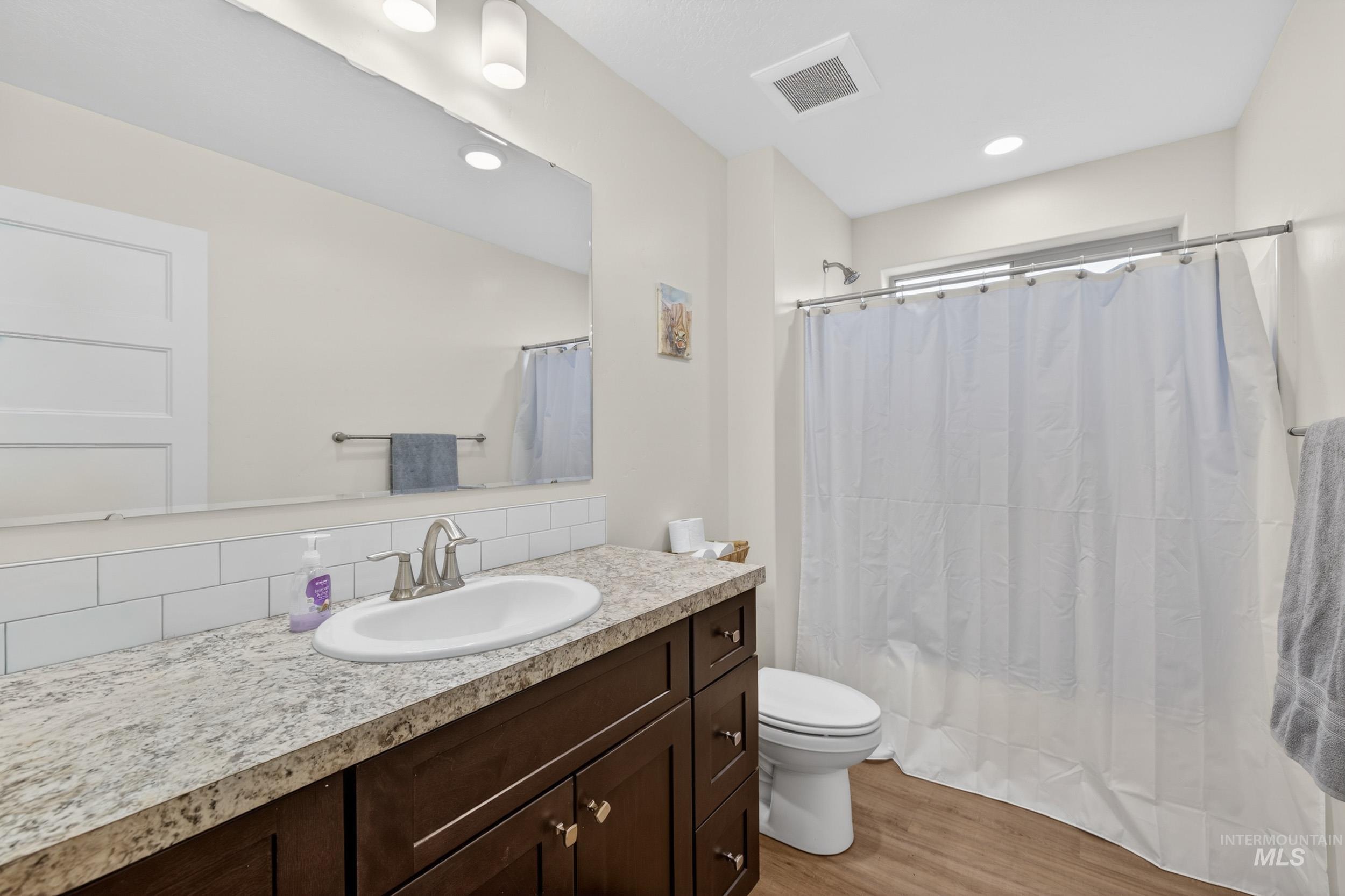 1854 Jacks Road Midvale, ID 83645 - Photo 9 of 16 Full bathroom featuring vanity, light wood finished floors, shower / bath combo, decorative backsplash, and recessed lighting