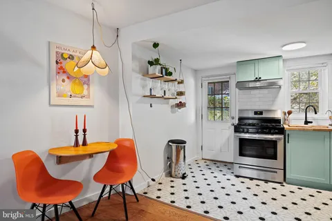 a kitchen with stainless steel appliances kitchen island granite countertop a refrigerator a stove a sink dishwasher a dining table and chair with the wooden floor