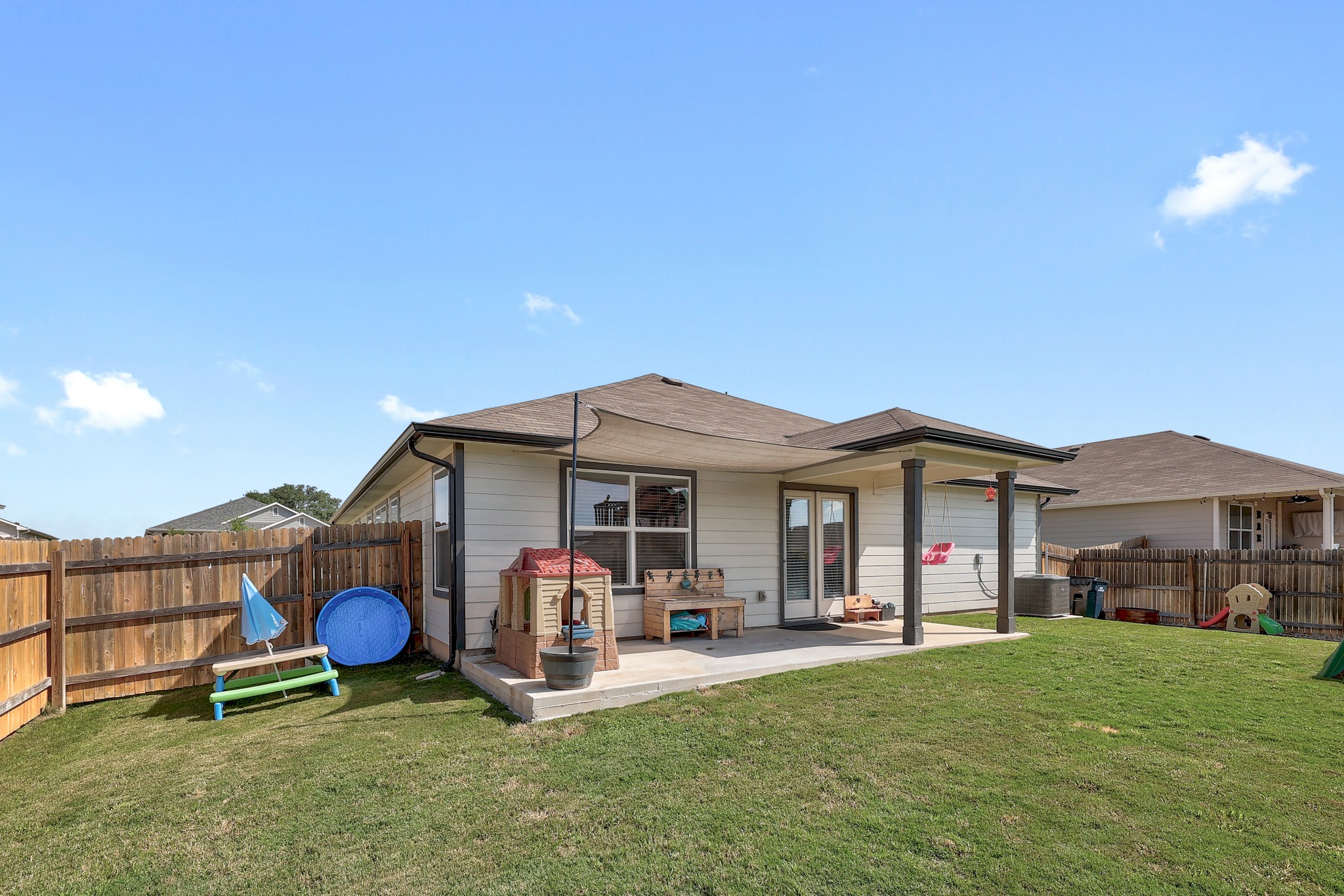 413 Hunter Loop Bertram, TX 78605 - Photo 27 of 27 A fenced backyard offers a concrete patio with a shaded seating area, perfect for outdoor enjoyment.