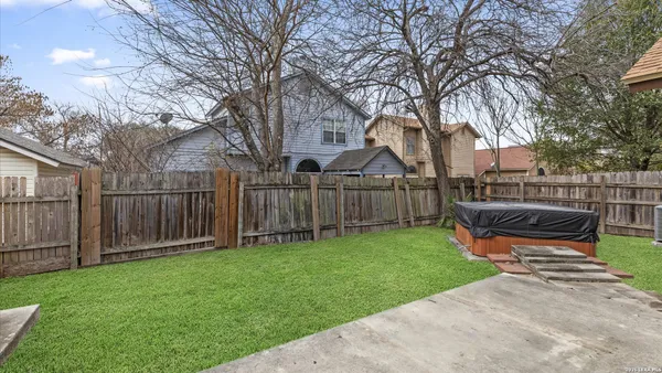 a view of a backyard with wooden fence and large trees