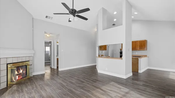 wooden floor in an empty room with a fireplace and a ceiling fan