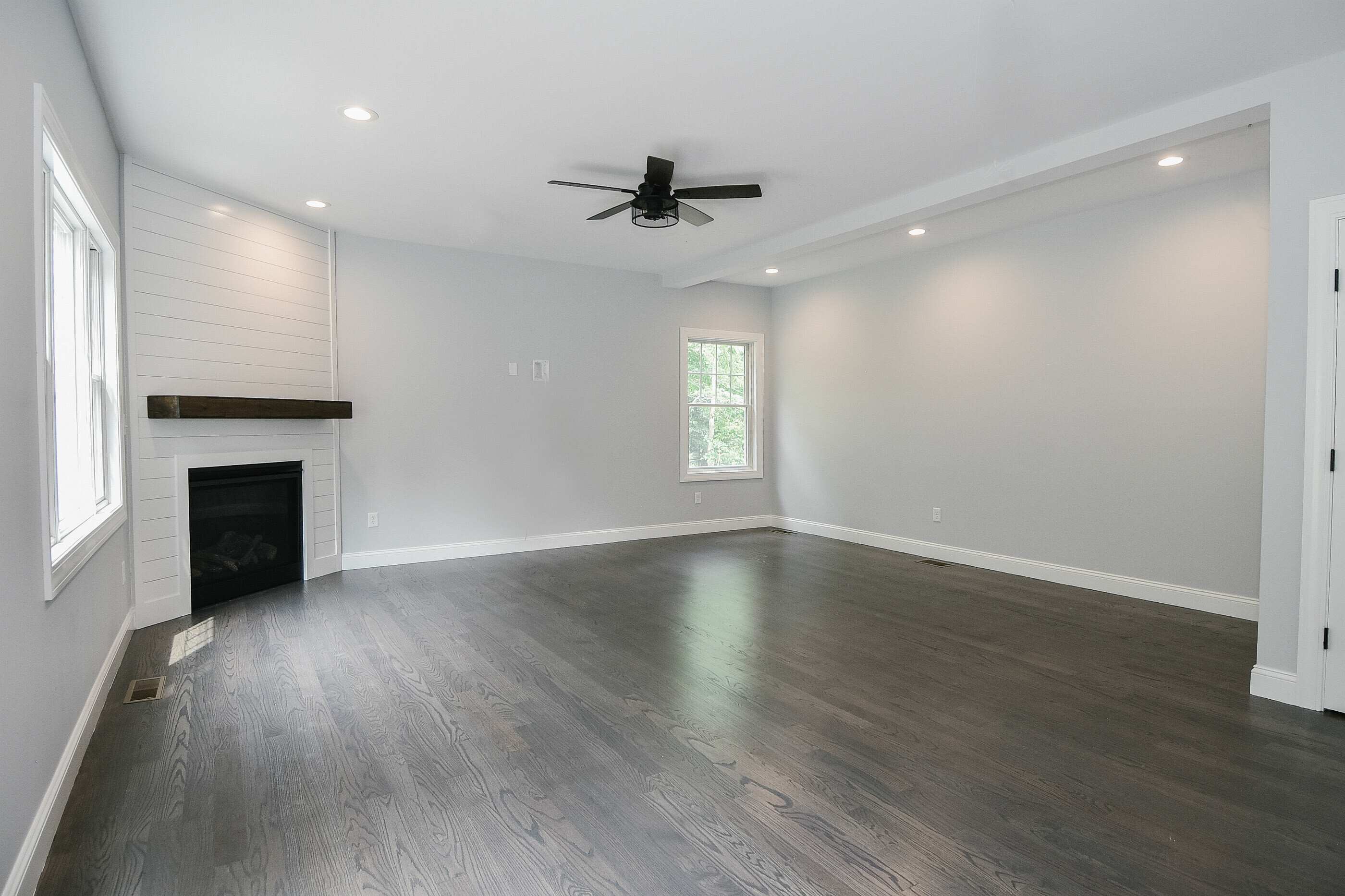 155 Old Common Road Wethersfield, CT 06109 - Photo 8 of 22 an empty room with wooden floor a ceiling fan a fireplace and windows