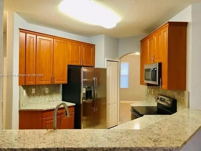 a kitchen with stainless steel appliances granite countertop a refrigerator and a sink