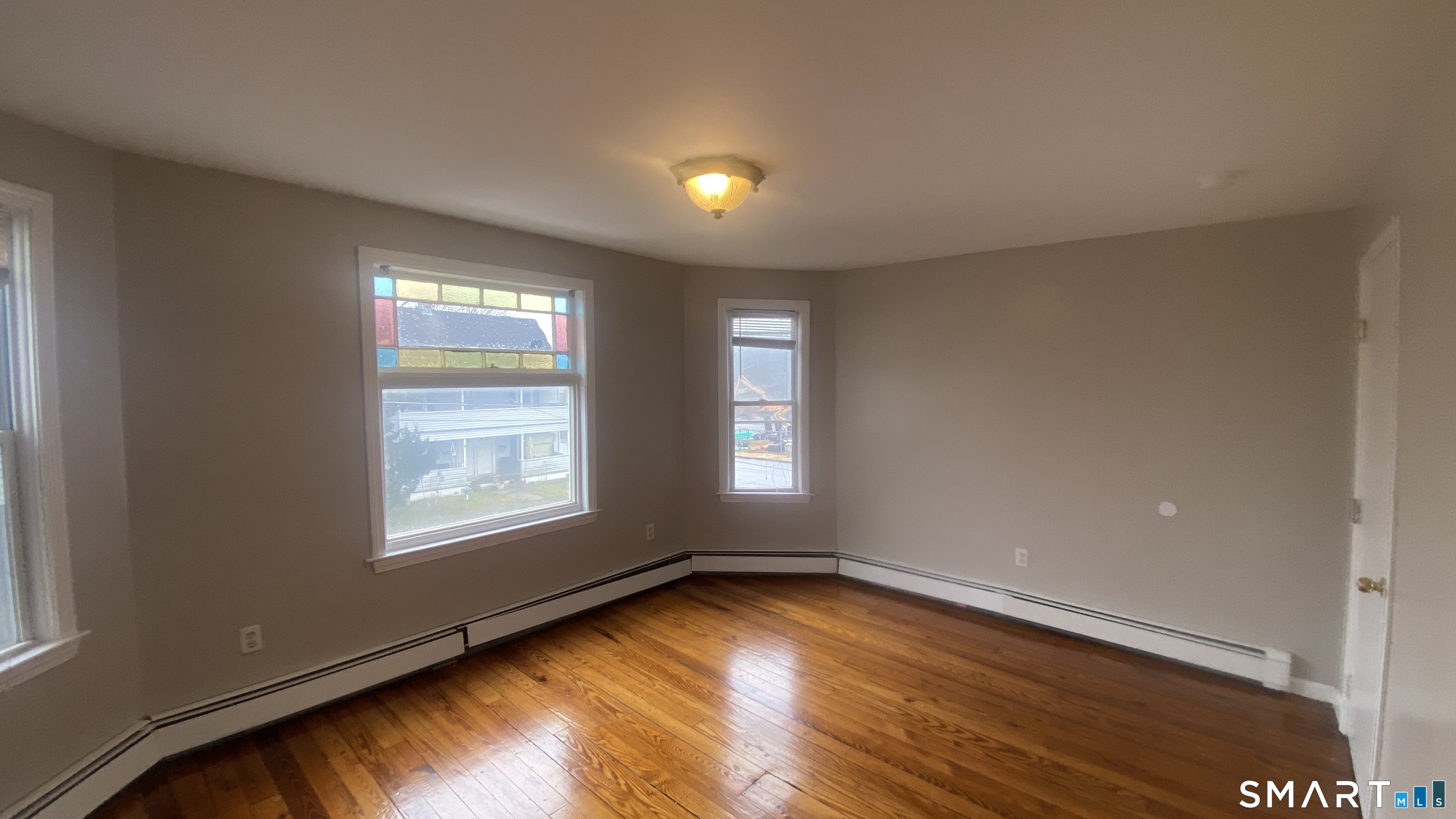 82 James Street, Unit 2 Torrington, CT 06790 - Photo 4 of 23 an empty room with wooden floor and windows