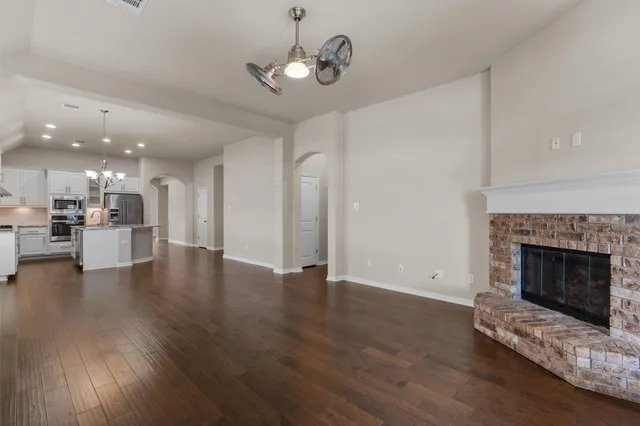 a view of an empty room with wooden floor fireplace and a window