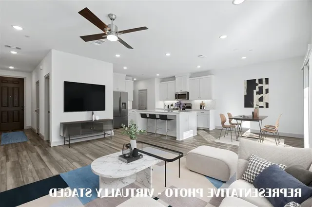 a living room with furniture kitchen view and a wooden floor