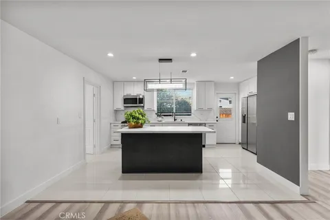 a living room with stainless steel appliances furniture a rug and a kitchen view