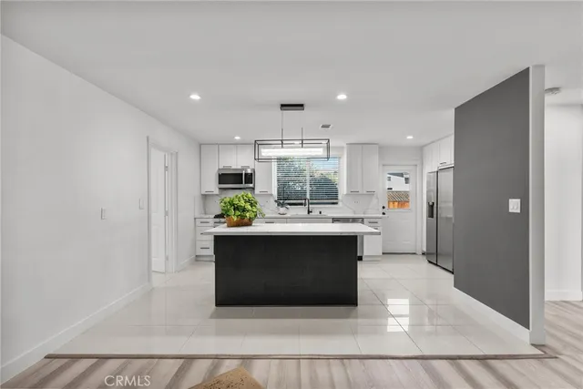 a living room with stainless steel appliances furniture a rug and a kitchen view
