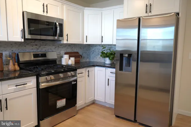 a kitchen with a stainless steel appliances white cabinet refrigerator and microwave