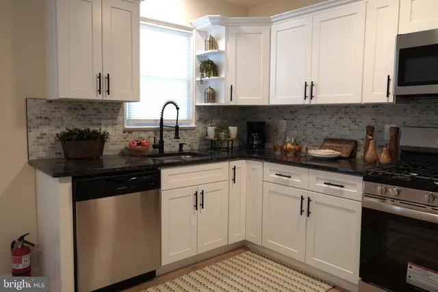 a kitchen with stainless steel appliances granite countertop white cabinets sink and stove