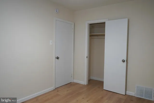 a view of an empty room with closet and wooden floor