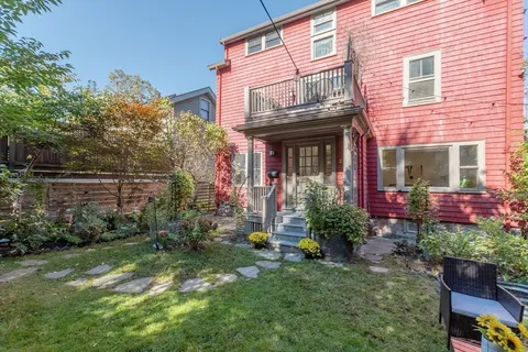 a view of a house with potted plants and a bench