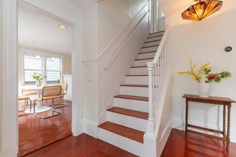 a view of a hallway to a livingroom with wooden floor and furniture