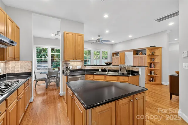 a kitchen with stainless steel appliances granite countertop a stove top oven a sink dishwasher and cabinets with wooden floor