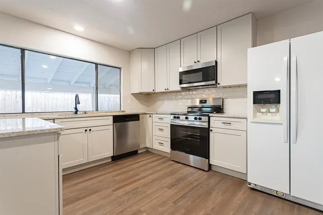a large white kitchen with a sink and dishwasher with a large window