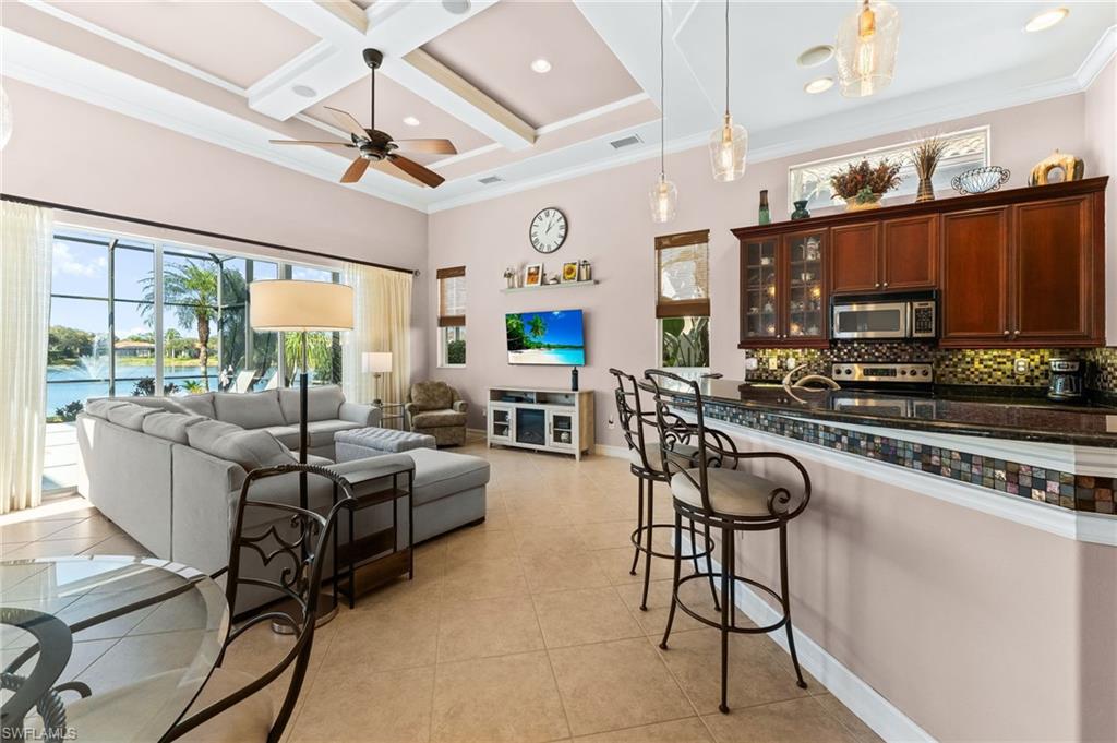 7875 Valencia Court Naples, FL 34113 - Photo 12 of 38 Kitchen featuring a kitchen island, crown molding, coffered ceiling, pendant lighting, and glass insert cabinets