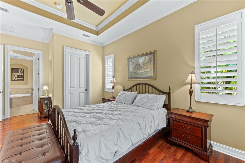 7875 Valencia Court Naples, FL 34113 - Photo 17 of 38 Bedroom with wood floors, a ceiling fan, crown molding, ensuite bath, and a tray ceiling