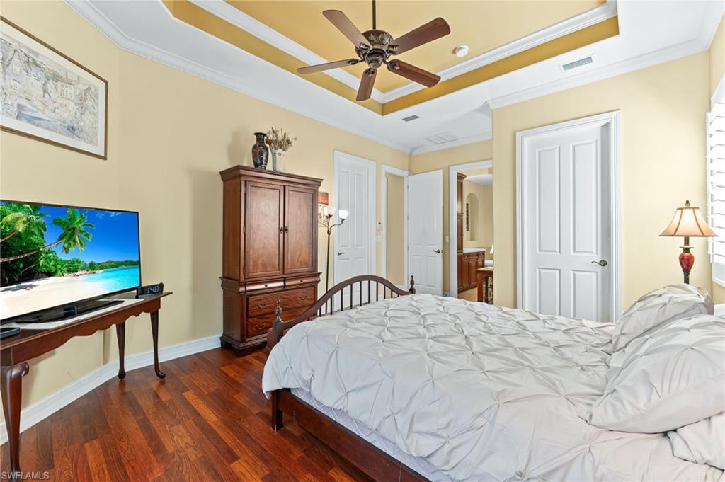 7875 Valencia Court Naples, FL 34113 - Photo 18 of 38 Bedroom with wood flooring, a raised ceiling, ceiling fan, ornamental molding, and connected bathroom
