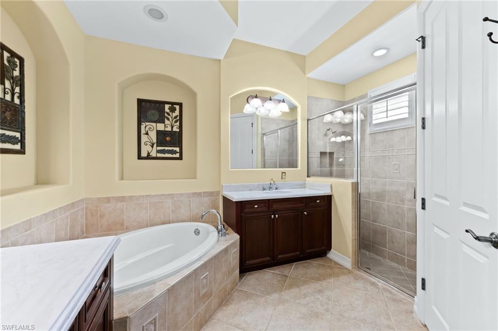 7875 Valencia Court Naples, FL 34113 - Photo 19 of 38 Bathroom with vanity, a garden tub, a stall shower, and light tile patterned flooring
