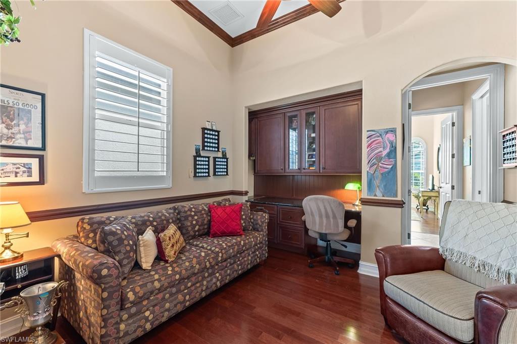 7875 Valencia Court Naples, FL 34113 - Photo 23 of 38 Home office with built in desk, wood floors, ornamental molding, arched walkways, and a ceiling fan