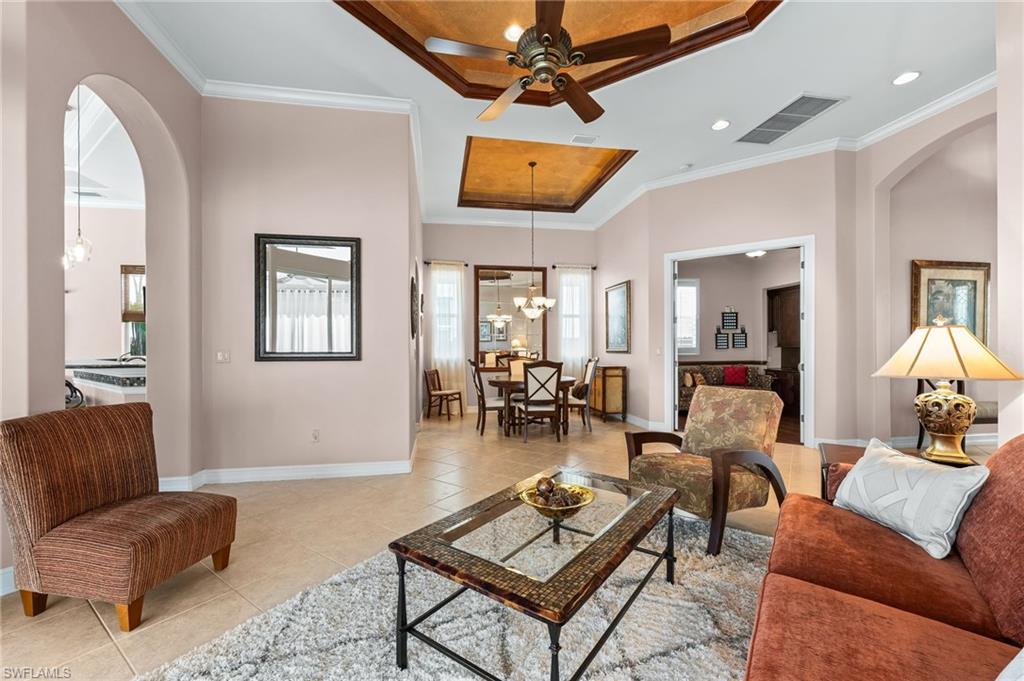 7875 Valencia Court Naples, FL 34113 - Photo 6 of 38 Living area featuring arched walkways, a ceiling fan, ornamental molding, tile patterned floors, and a tray ceiling